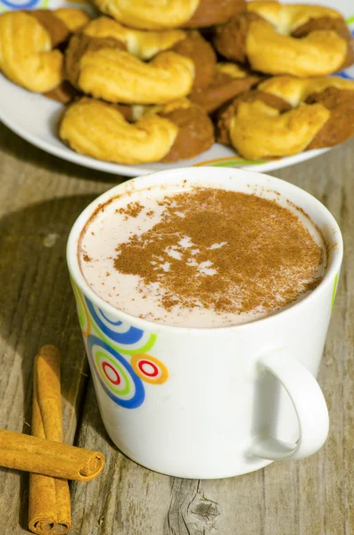Hot choclolate in white mug with cinnamon and biscuits on wood — Stock Photo, Image
