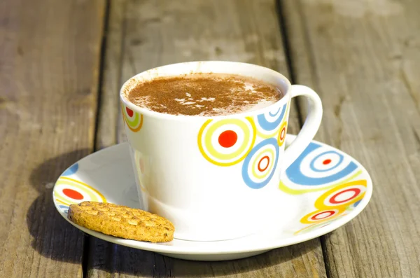 Hot chocolate with cinnamon and biscuit on wood — Stock Photo, Image