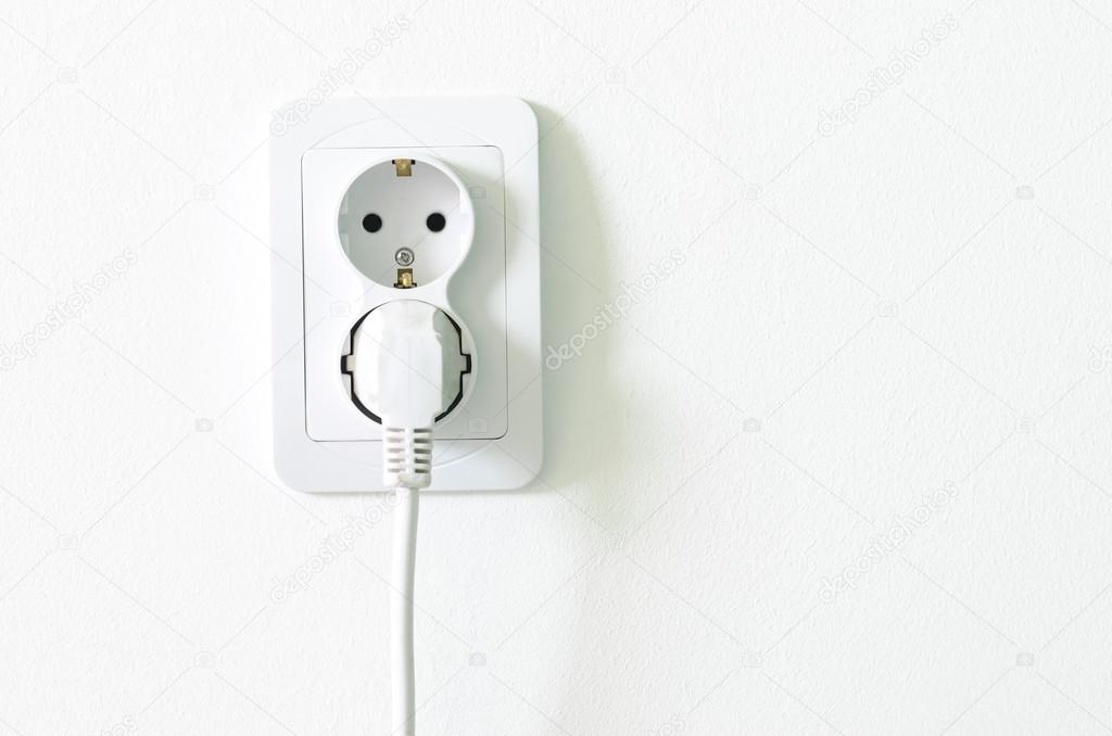 European white electrical outlet socket pluged in on white wall Stock