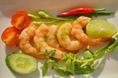 Izgara karides, biber ve baharatlı yeşil soslu taze sebze. Beyaz bir tabakta.