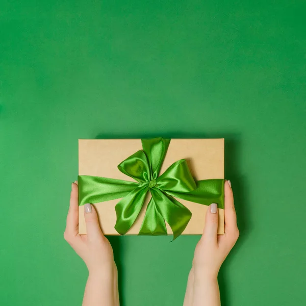 Жінка тримає подарункову коробку на зеленому столі — стокове фото