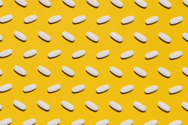 Лекарственные таблетки и таблетки на желтом фоне — стоковое фото