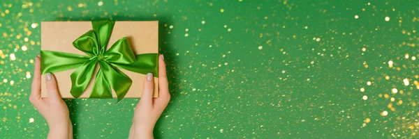 Žena drží dárek box na zeleném stole — Stock fotografie