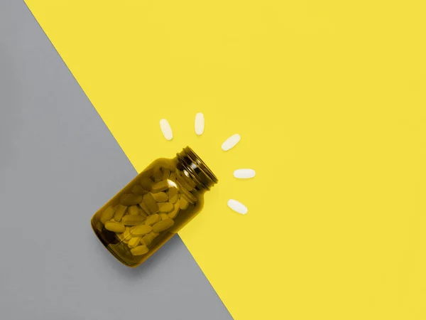 Медицинские таблетки на желтом и сером фоне — стоковое фото