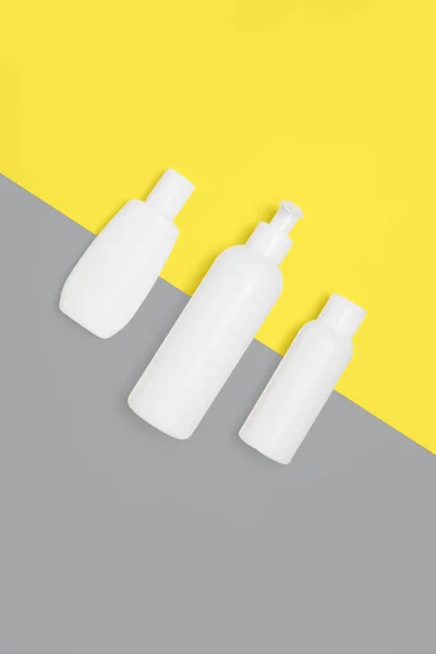 Sarı ve gri arka planda kozmetik şişeleri