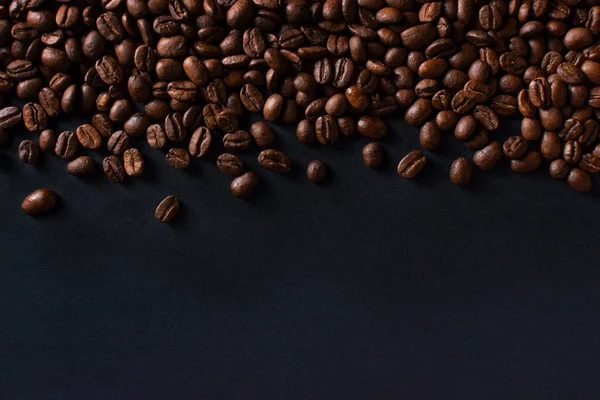Свежий кофе в зернах на черном фоне — стоковое фото