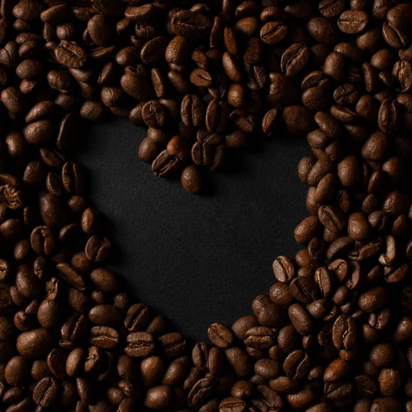 Кофейные зерна с сердцем на черном фоне — стоковое фото