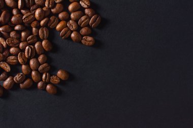 Taze kavrulmuş kahve çekirdekleri siyah taş arka planda yakın plan. Üst görünüm, kopyalama alanı olan düz uzanma