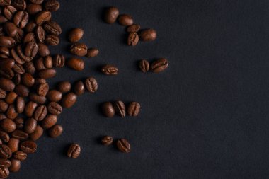 Taze kavrulmuş kahve çekirdekleri siyah taş arka planda yakın plan. Üst görünüm, kopyalama alanı olan düz uzanma
