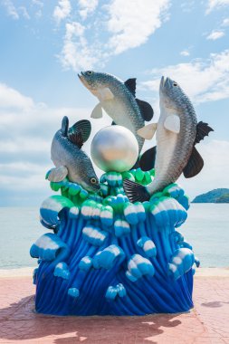 Lively fish and pearl statue on the shore, Thailand. clipart