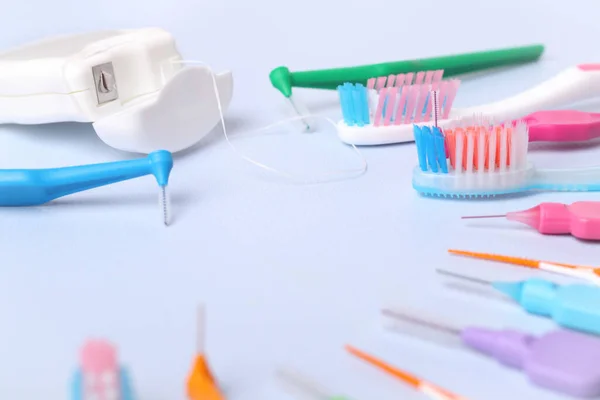 Toothbrushes, dental floss and interdental toothbrushes on blue background, small depth of focus. Dental and orthodontic concept.