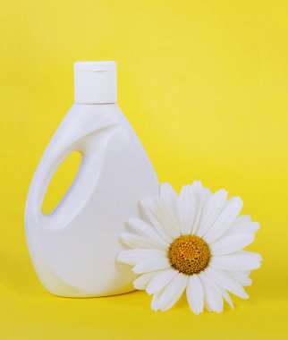 Sarı arka planda papatya olan beyaz bir şişe sıvı sabun.