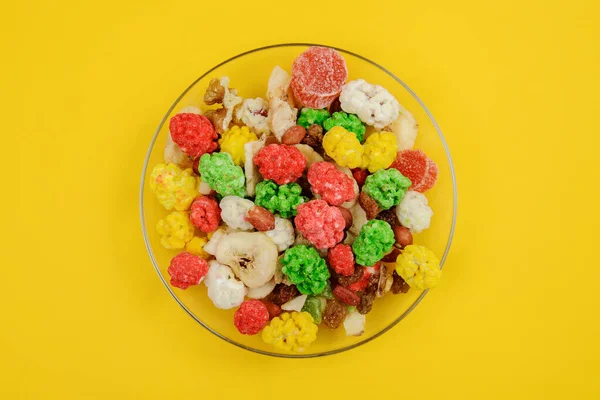 混合坚果 干果和糖果仁 核桃仁 彩糖花生 糖果糖 葡萄干和香蕉片在玻璃盘黄色背景的清洁核 顶部视图 健康食品概念 — 图库照片