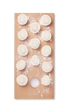 Tahta tahtada, beyaz arkaplanda izole edilmiş çiğ ravioli (veya hamur köfteleri) grubunun üst görünümü.