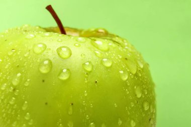 Yeşil arkaplana karşı taze yeşil elma üzerine su damlalarını kapatın, küçük bir odak derinliği.