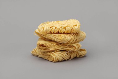 Gri arka planda bir yığın kuru yumurta eriştesi (makarna yuvaları).