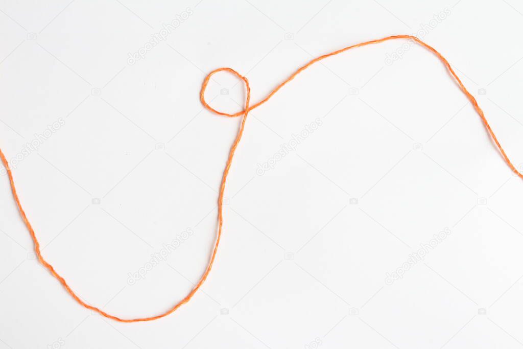 Orange thread on a piece of paper.