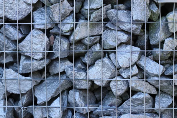 The texture of stones in a metal grid painted with gray paint.