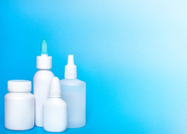 Mavi arka planda şişe maketi. Şişe, haplar, kapsüller.