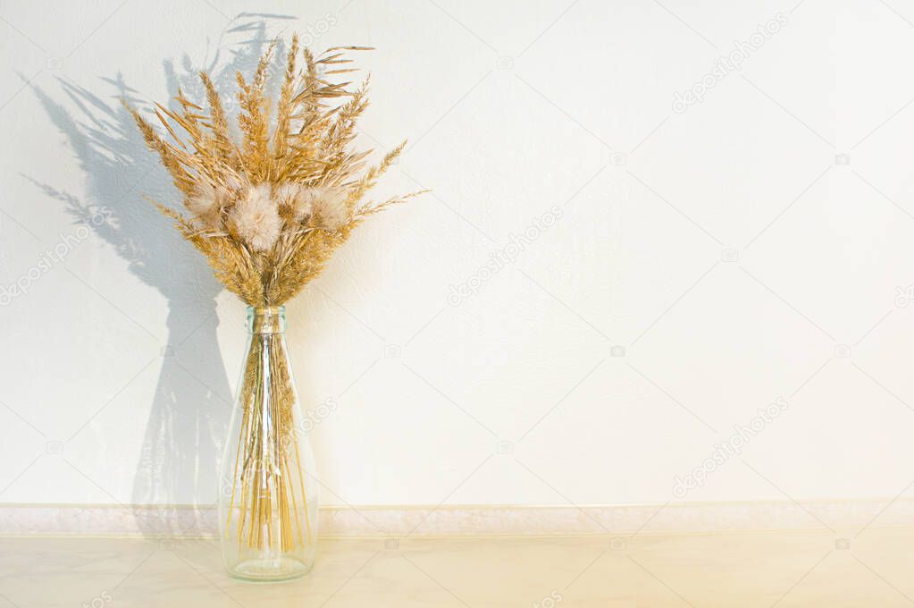 Bouquet of dried flowers in a glass bottle on table.