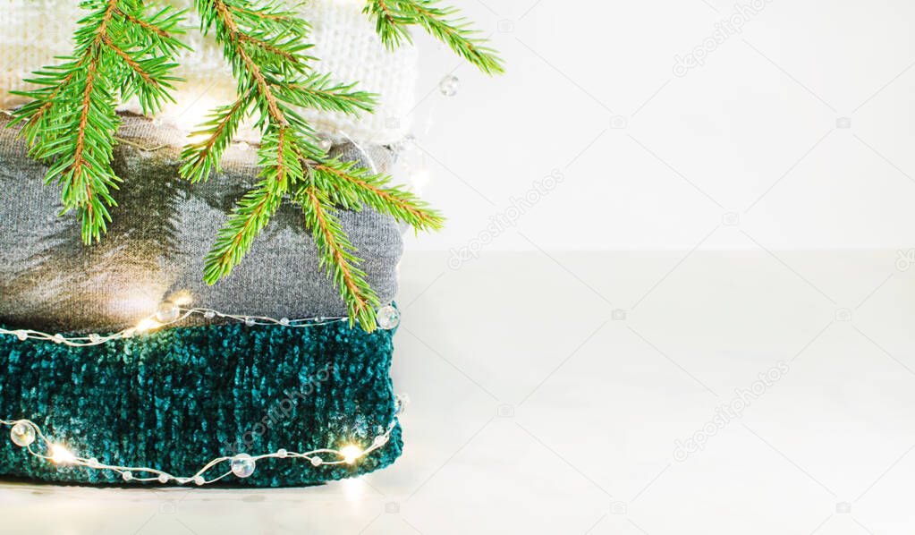 stack of three sweaters, garland and pir branch with copy space
