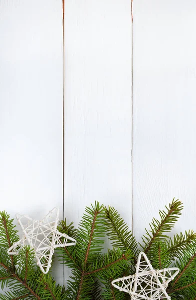 크리스마스 장식을 하고 있는 초록빛 전나무 가지들과 흰 나무판 위의 별들 — 스톡 사진