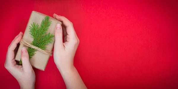 Kırmızı arka planda köknar dalları olan hediye kutusu.