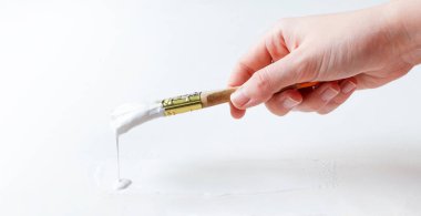 El fırçayı tutar ve beyaz yüzeyi boyar.