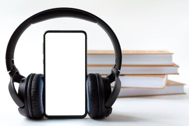 Kitapların arka planında telefon ve kulaklık var. Teknoloji ya da klasik konsept seçimi.