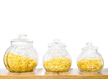 Raflardaki şeffaf kavanozlarda beyaz arka planda izole edilmiş makarna..