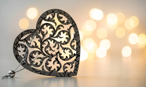 Gri bir zemine oyulmuş ahşap kalp altın bir bokeh ve kopyalama alanı ile