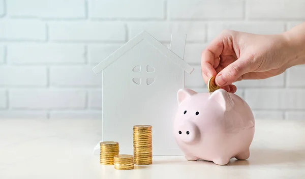 Piggy coin bank, coin and house model on white background. Savings for buying house concept. Real estate market