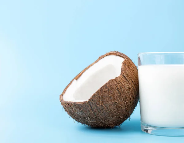 Kokosmelk in een glas en kokosnoot op blauwe achtergrond met kopieerruimte — Stockfoto