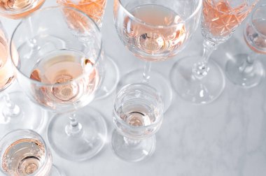 Gri arka planda farklı bardaklarda köpüklü gül şarabı.