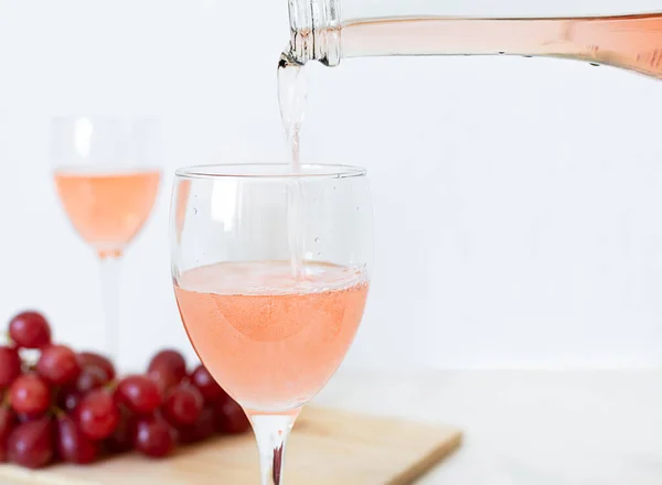 Vinho rosa é derramado em um copo de uma garrafa — Fotografia de Stock