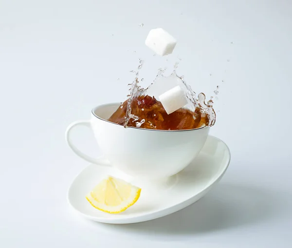 Tabağa bir dilim limon ve çay fincanına damla damla düşen şeker. havalanma ve denge
