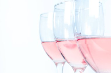 Beyaz arka planda gül şarabı olan üç bardak yakın plan.