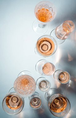 Gri arkaplanda farklı bardaklarda köpüklü gül şarabı.