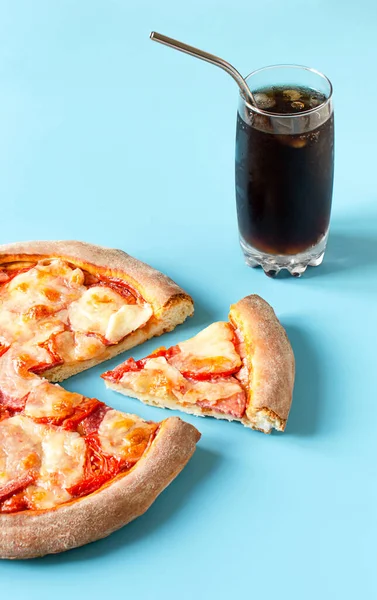 pizza and slice of pizza on a blue background and soda with ice and a metal straw. fast food and copy space.