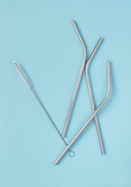 tekrar kullanılabilir çelik pipetler ve mavi arka planda fırçalar.