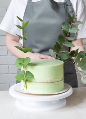 Pasta şefi yeşil pastayı okaliptüsle süslüyor..