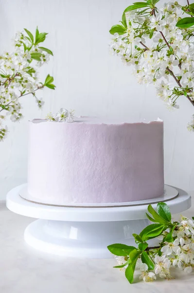 Pastel rosado de boda en un stand entre ramas de flores de cerezo — Foto de Stock