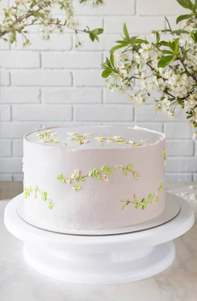 La torta de boda rosada sobre el soporte entre las ramas de los cerezos. delicada decoración en la torta — Foto de Stock