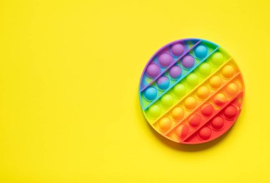 Modern oyuncak anti-stresi patlat. Kopya alanı ile sarı arkaplanda gökkuşağı oyunu