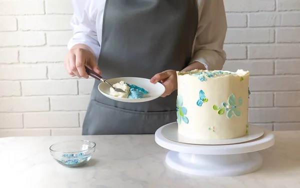 Panadero femenino decorando con crema sabrosa torta en la mesa — Foto de Stock