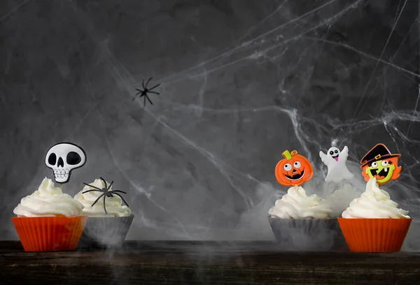 Spaventosi cupcake di Halloween su uno sfondo scuro con ragnatele e fumo Foto Stock Royalty Free