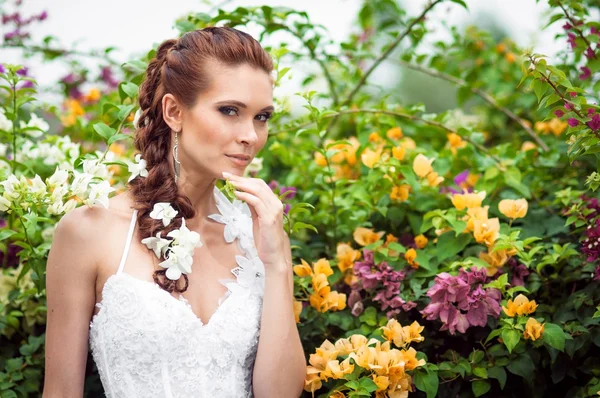 The bride in a lush garden surrounded by flowers — Stock Photo, Image