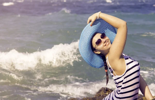 Hermosa mujer sentada en una piedra y salpicando en el mar. Estilo vintage —  Fotos de Stock