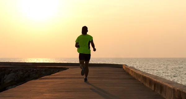 Мужчина бежит по пляжу на закате — стоковое фото