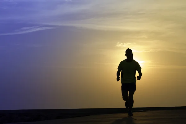 Man som springer på stranden vid solnedgången — Stockfoto
